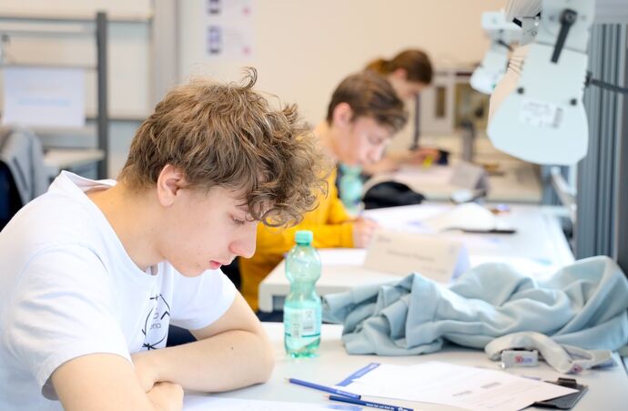 Teilnehmende der Finalrunde der PhysikOlympiade 2024 brüten am DESY in Hamburg über den Aufgaben.