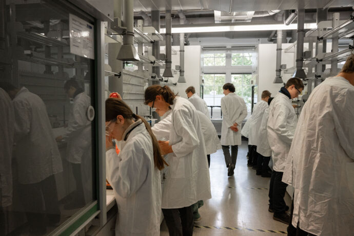 Schüler:innen bei der Laborarbeit unter der Aufsicht eines Betreuers